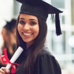 usmiechnięta studentka trzymająca dyplom